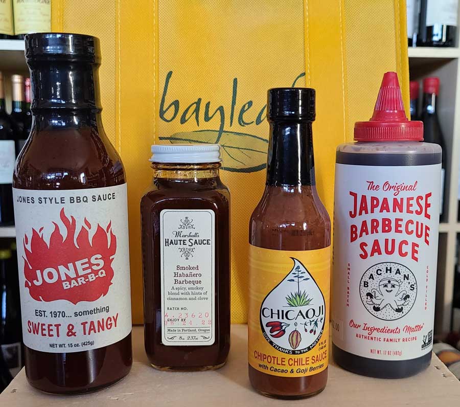 four bottles of barbecue sauce are sitting on a table .