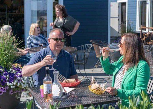 a man and a woman are sitting at a table drinking wine .