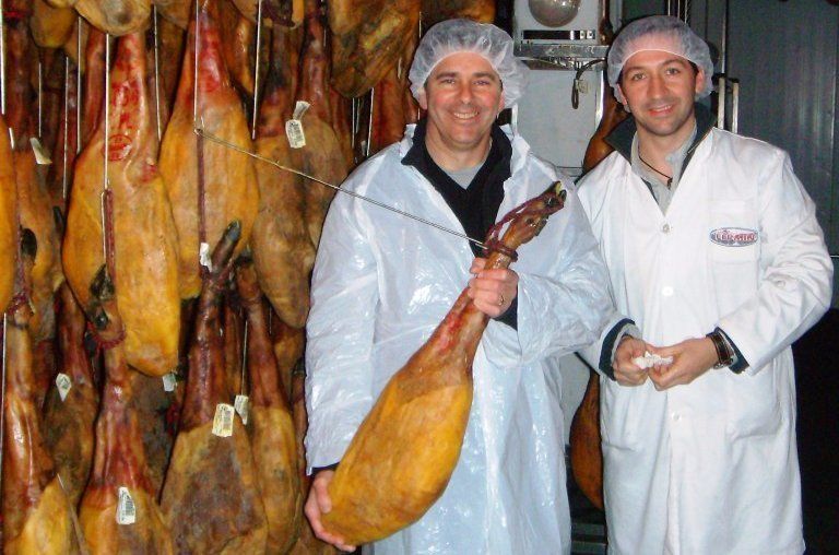 two men standing next to each other holding a large piece of meat