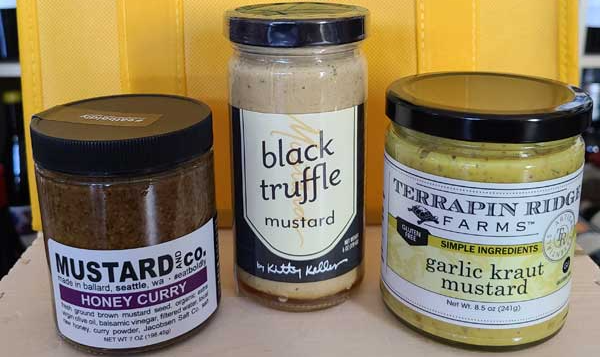 three jars of mustard are sitting on a table .