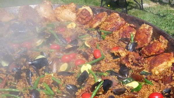 a large pan filled with rice , meat , vegetables and smoke coming out of it .