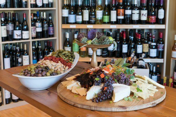 a wooden cutting board filled with cheese , grapes , olives , and other foods .