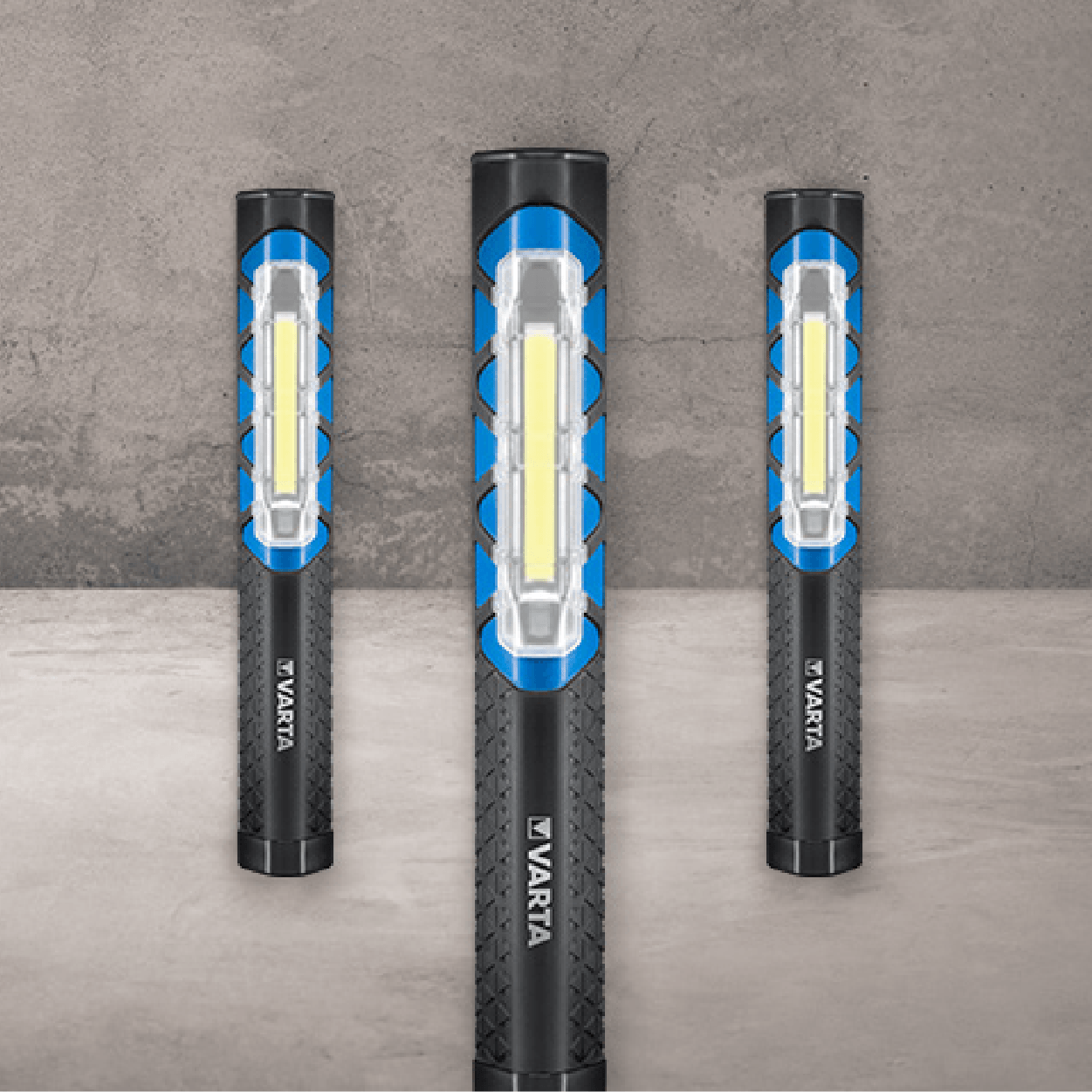 Three Varta work lights with blue accents and a white light bar, standing on a gray background.