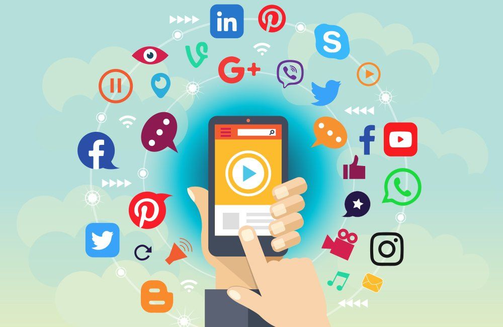 A person is holding a cell phone with social media icons surrounding it.