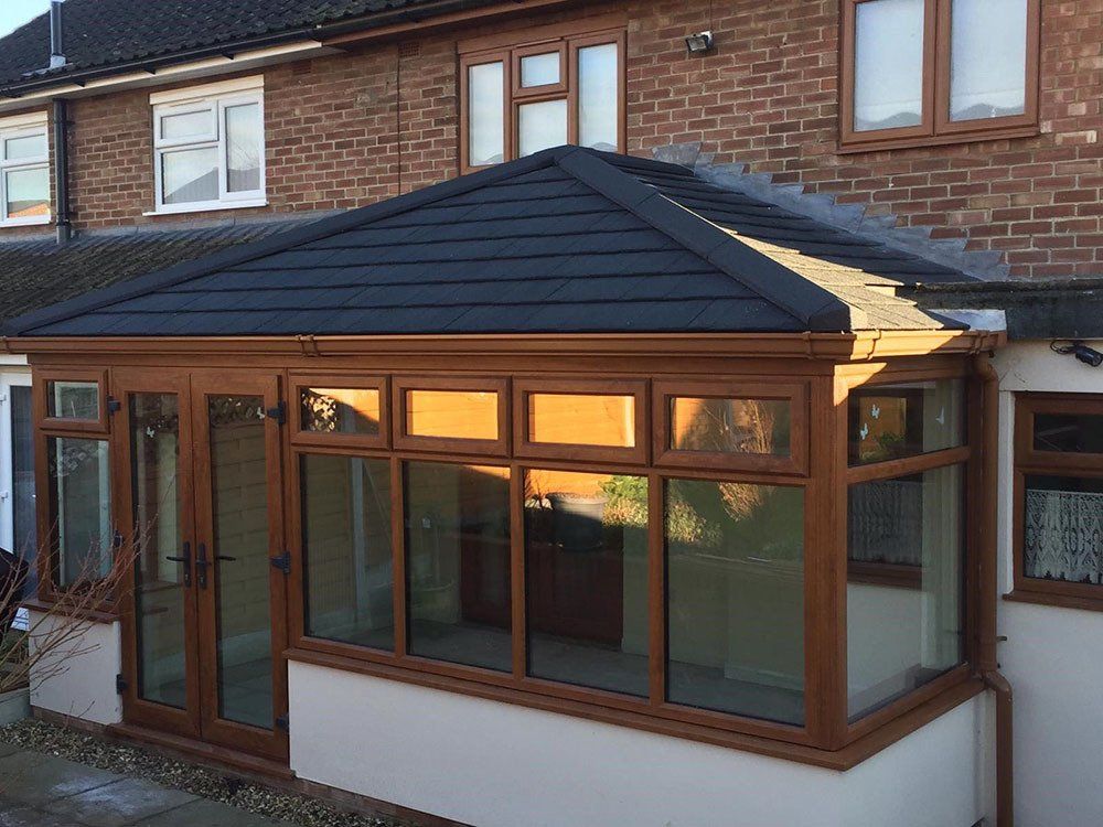UPVC grained effect conservatory with rendered dwarf wall and Guardian Warm Roof with Metrolite tiles – Great Blakenham, Ipswich