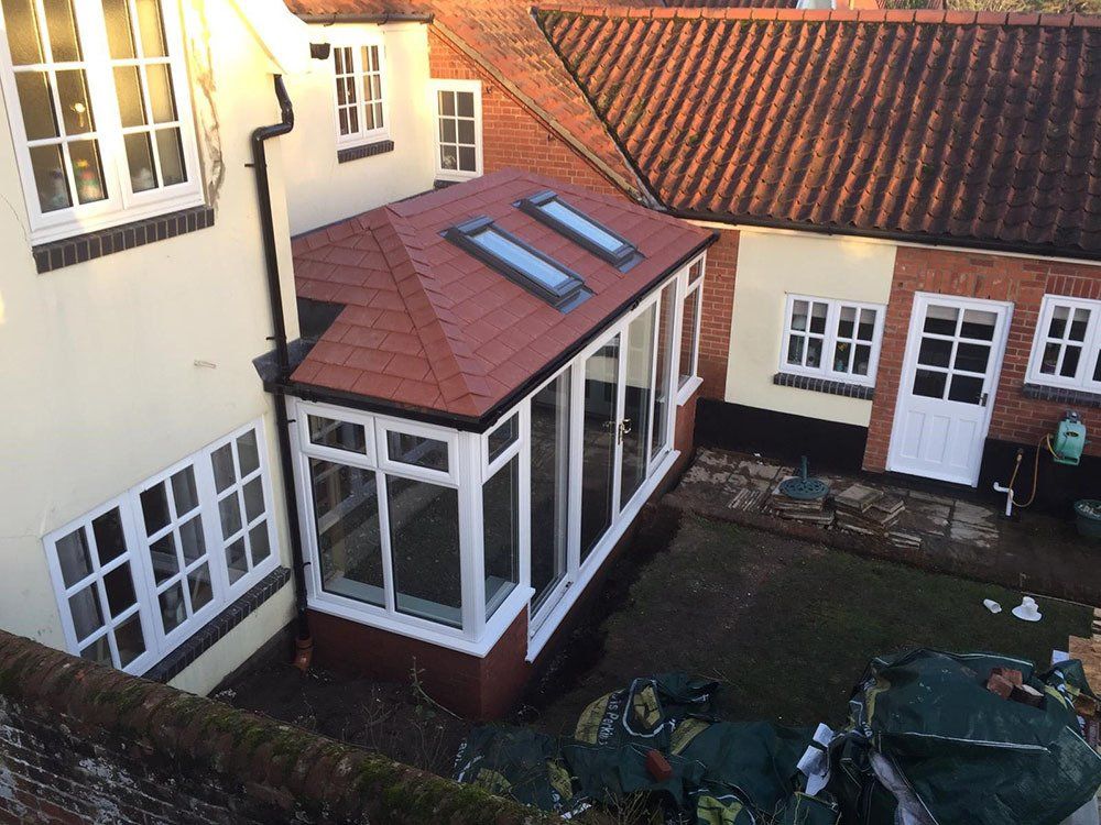 Double-hipped Edwardian conservatory with Guardian Warm Roof, two Velux windows and slate effect tiles. An excellent quality finish in a limited and awkward space – Loddon, Norwich
