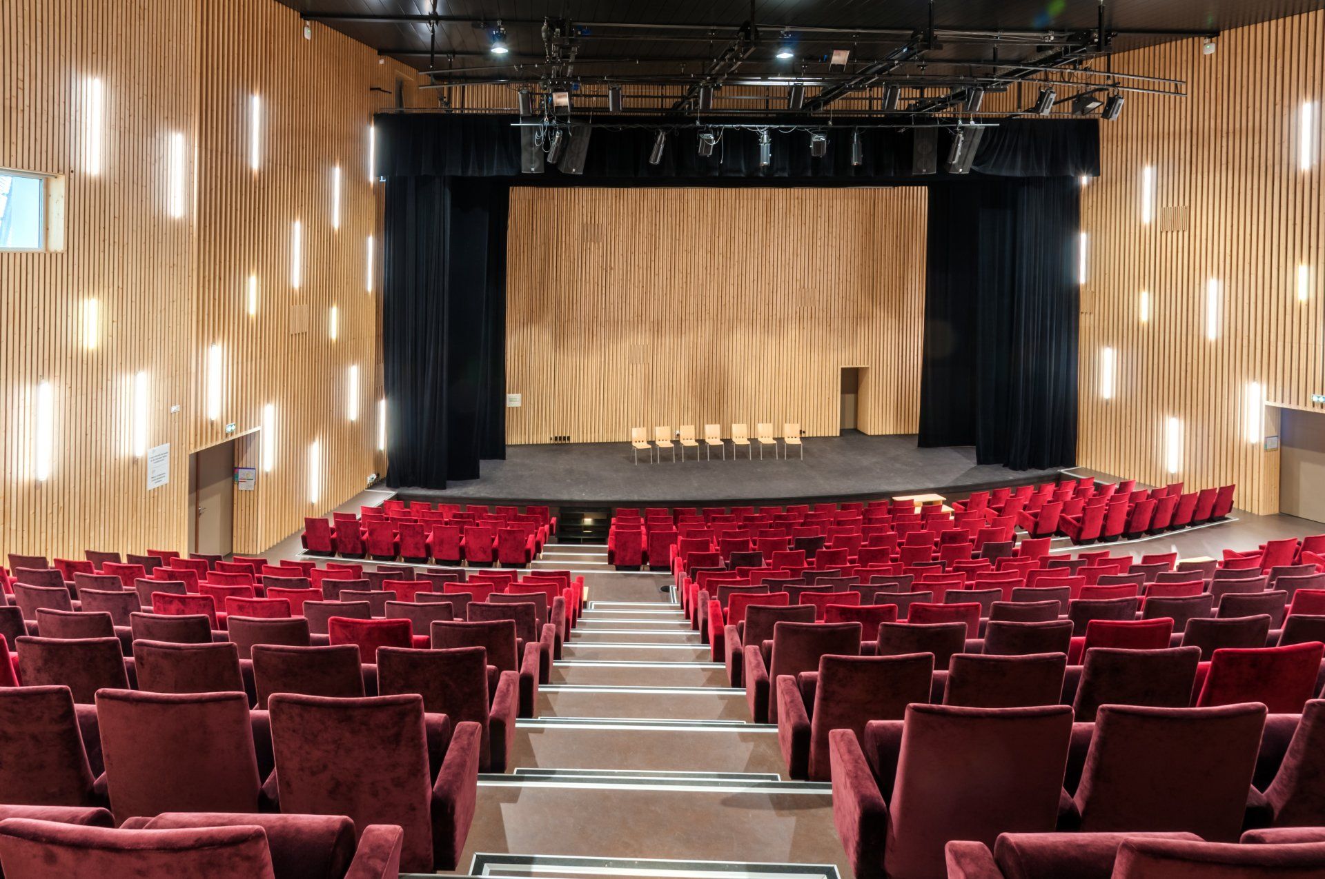 Un grand auditorium avec des sièges rouges et une scène.