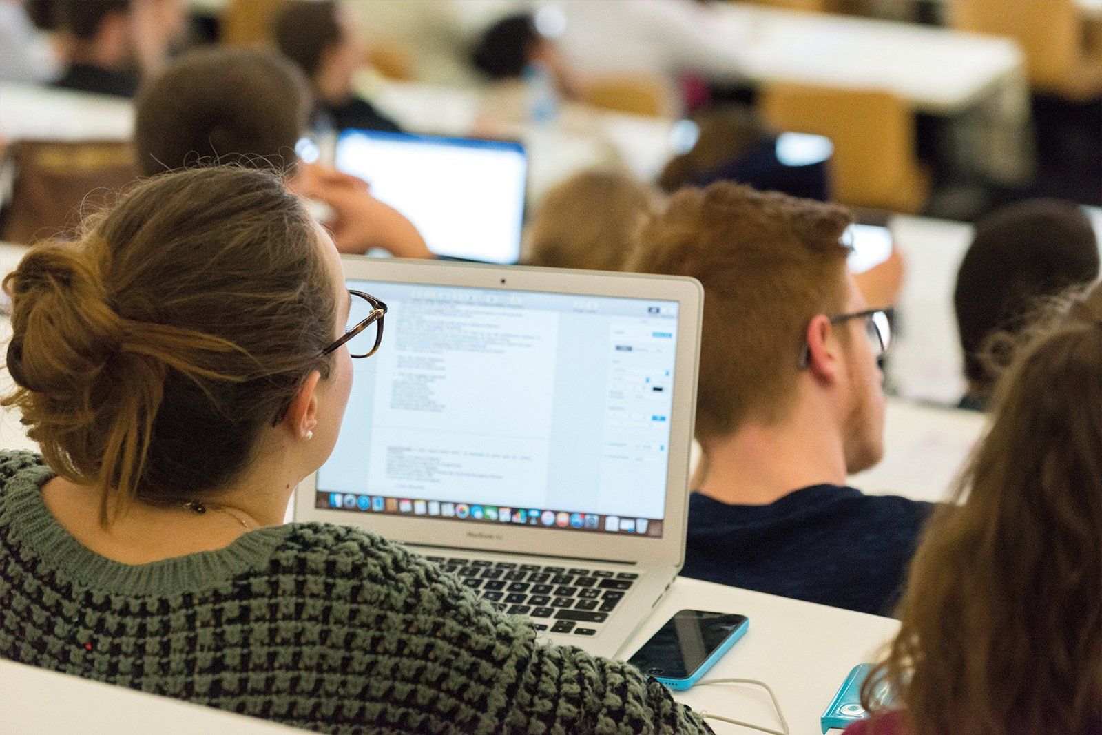 Une femme est assise devant un ordinateur portable dans une salle de conférence.