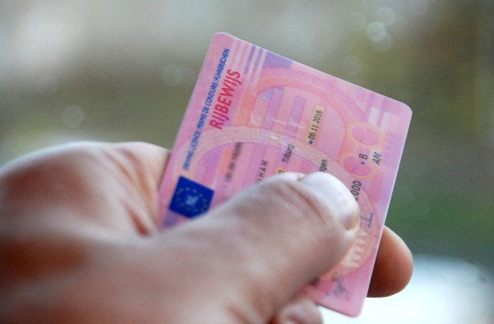 Een hand houdt een roze Nederlands rijbewijs vast