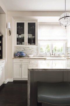 A kitchen with white cabinets , stainless steel appliances , a sink , and a large island.