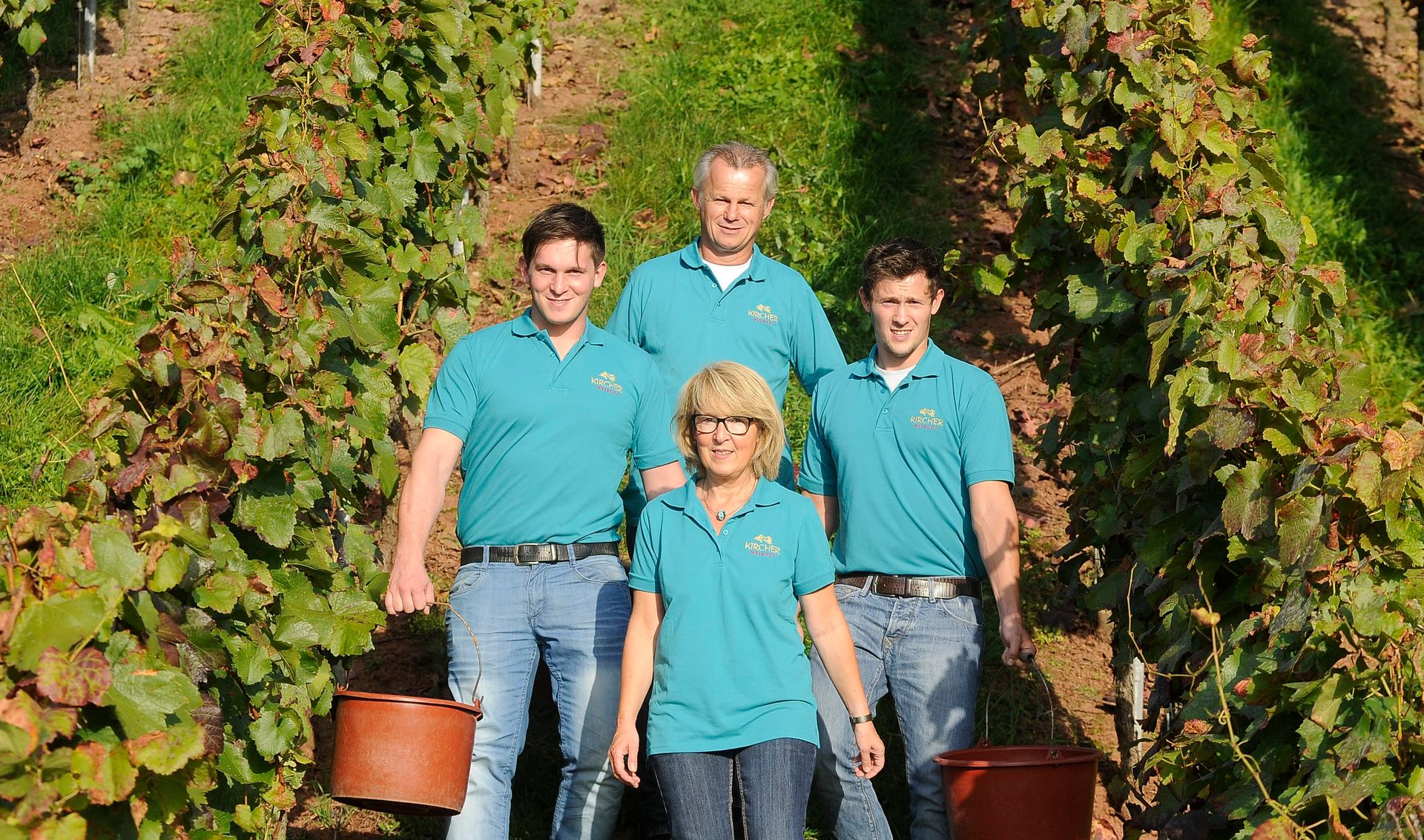 Eine Gruppe von Menschen posiert in einem Weinberg für ein Foto.