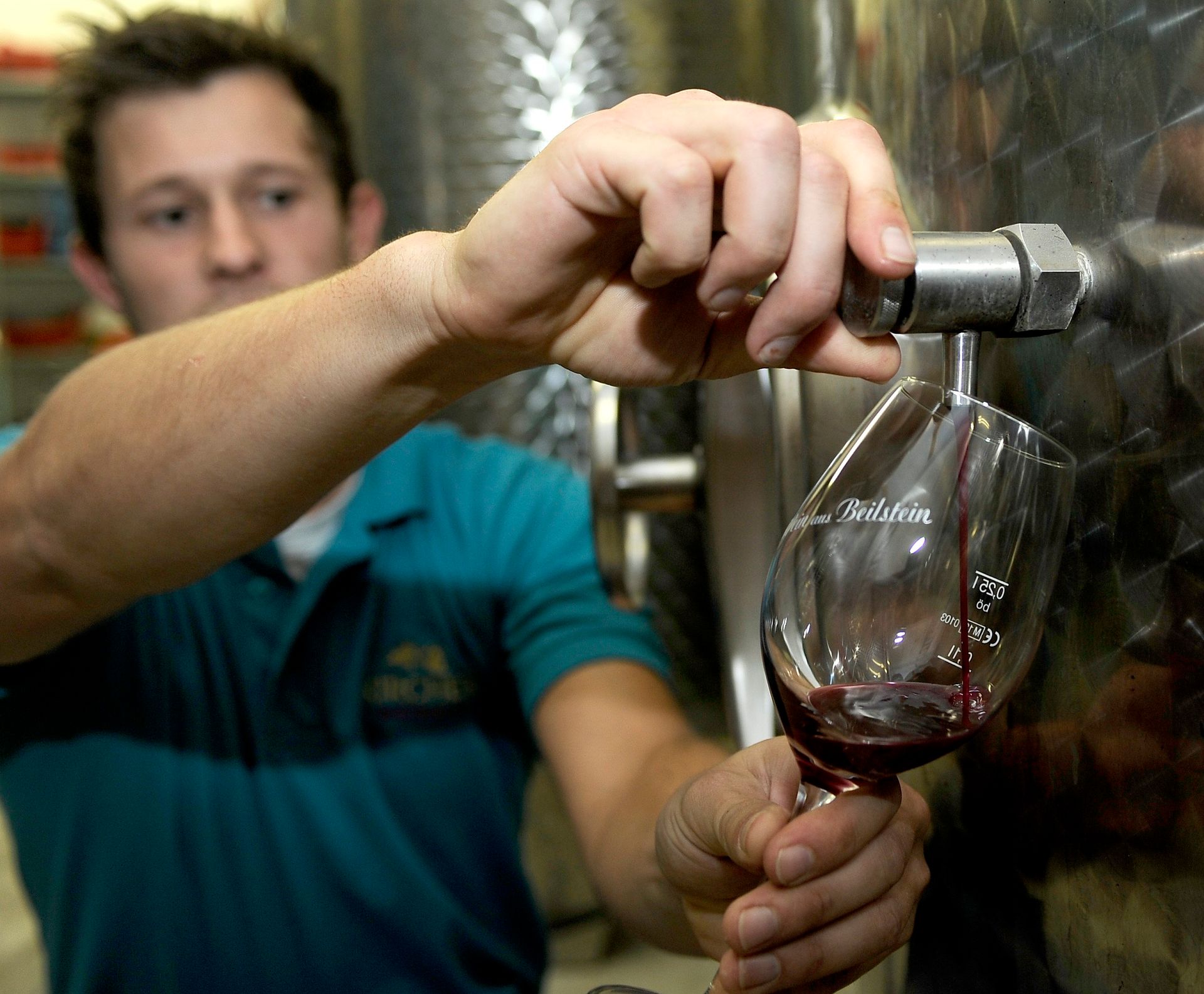 Ein Mann in einem blauen Hemd gießt Wein in ein Glas