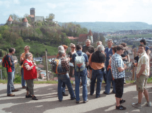 Eine Gruppe von Menschen steht auf einer Straße mit einer Burg im Hintergrund