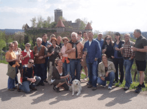 Eine Gruppe von Menschen posiert für ein Foto mit einem Hund vor einem Schloss