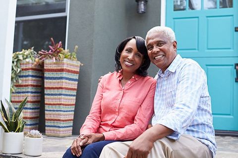 A senior couple sits on their front steps.