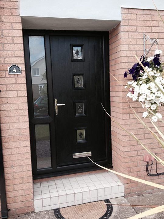 Front entrance with black door, pink brick walls, and a hanging flower basket