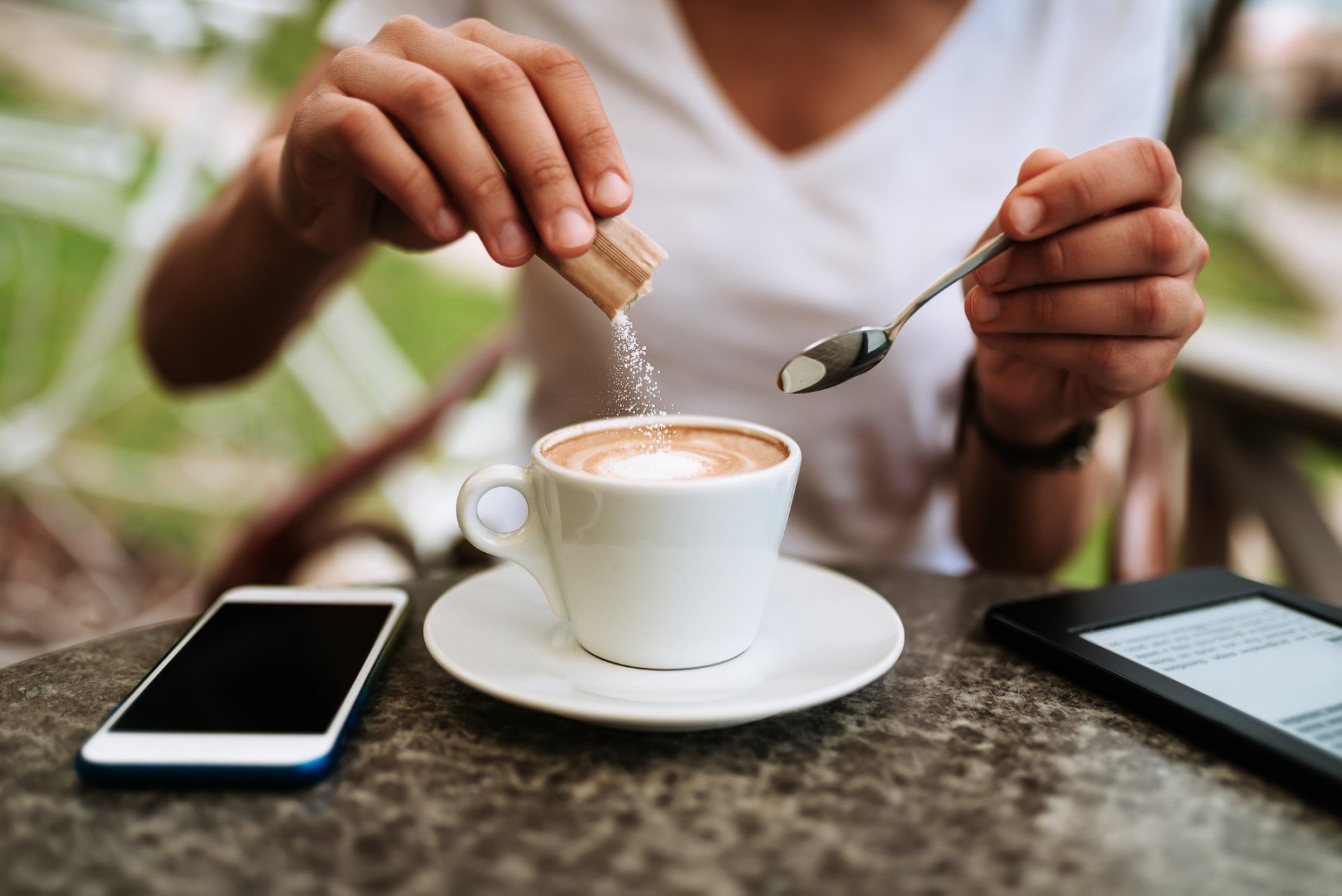 Una persona está echando azúcar en una taza de café.