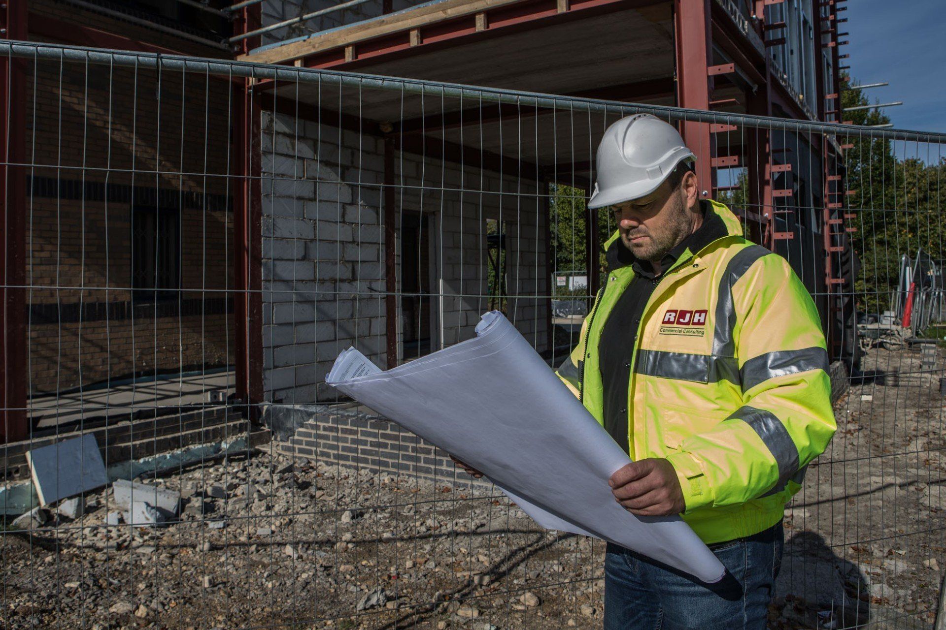 A man in a hard hat is looking at a blueprint on a construction site.