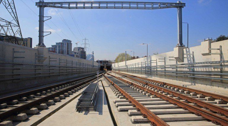 A train track going into a tunnel with a city in the background.