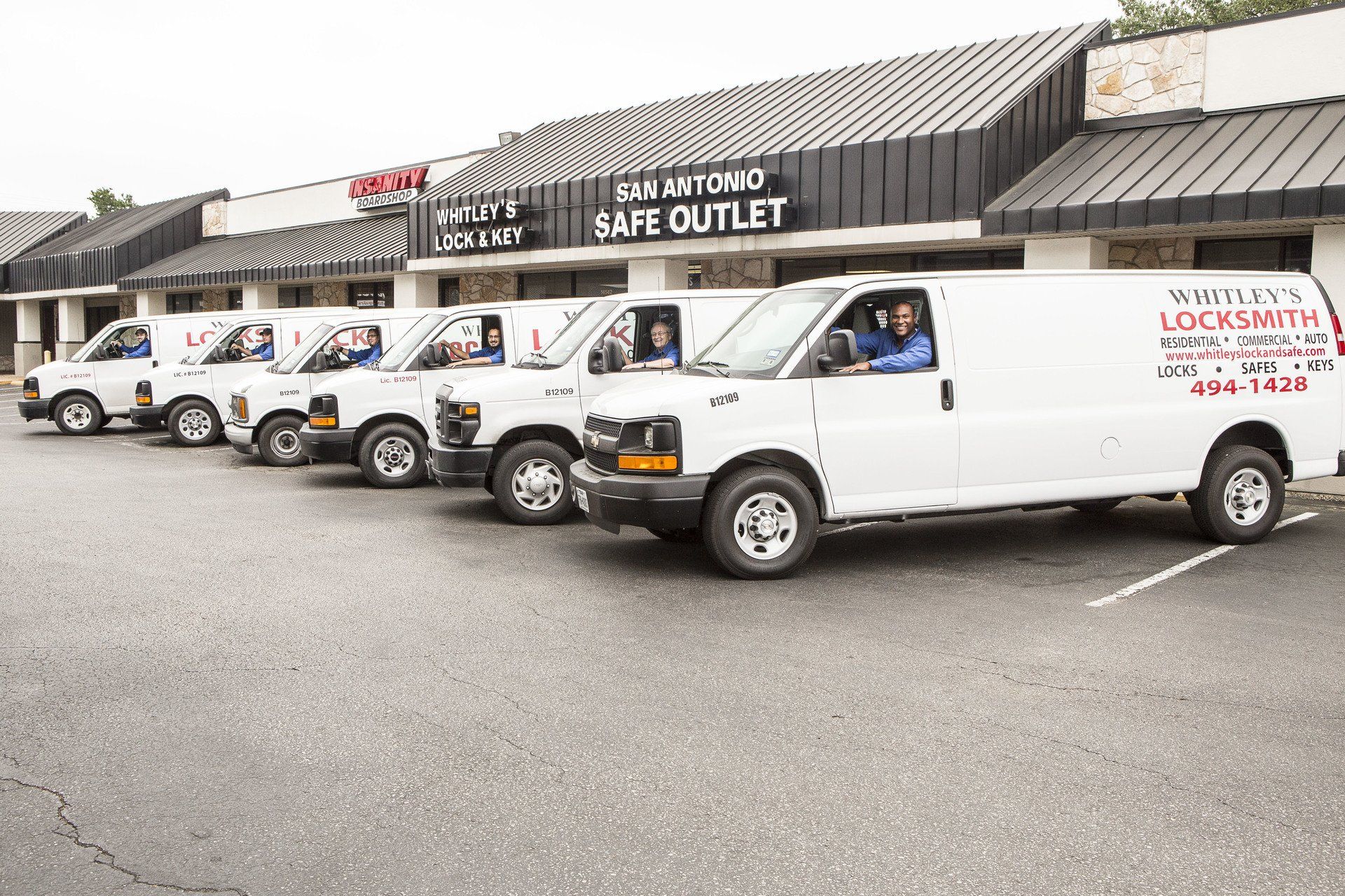 A row of white vans parked in front of a building.
