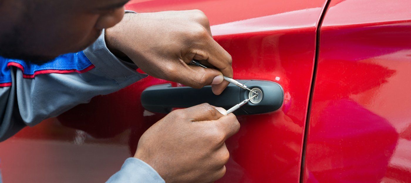 A man is trying to open a car door with a key.