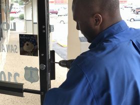 A man in a blue shirt is working on a door with a drill