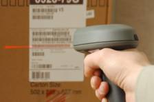 Manuelles Scannen eines Barcode-Etiketts auf einem Karton mit einem roten Laser.