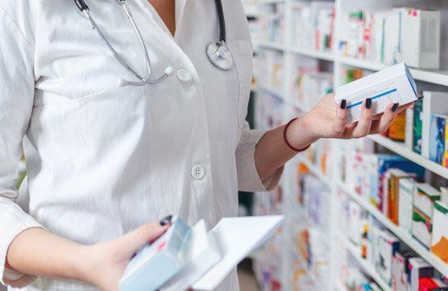 farmacista prende un farmaco in mano da uno scaffale