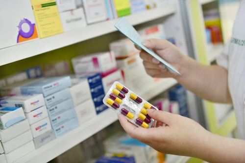 farmacista mentre consulta una ricetta e tiene in mano delle pillole