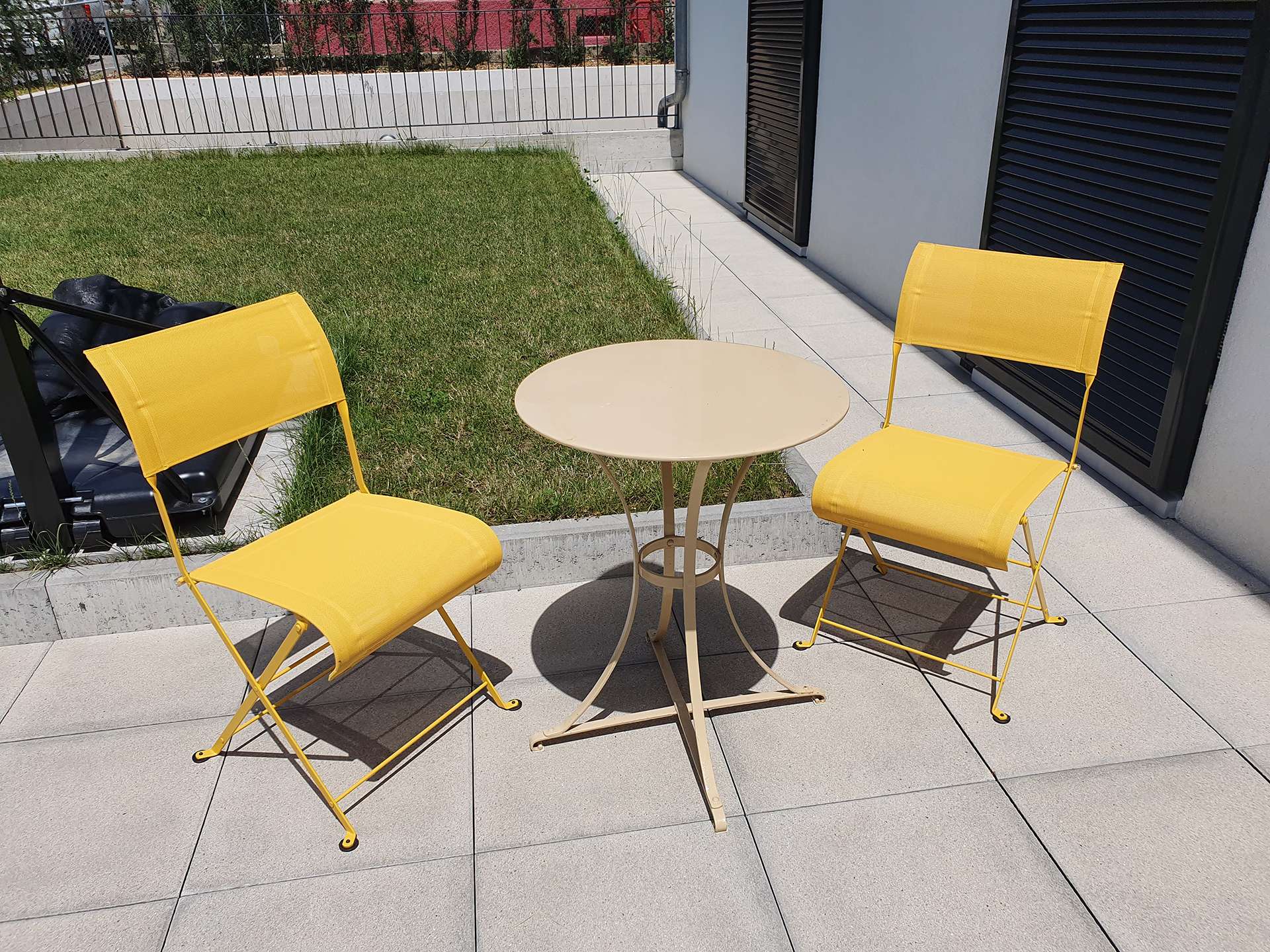 Une table beige et deux chaises jaune sur une terrasse