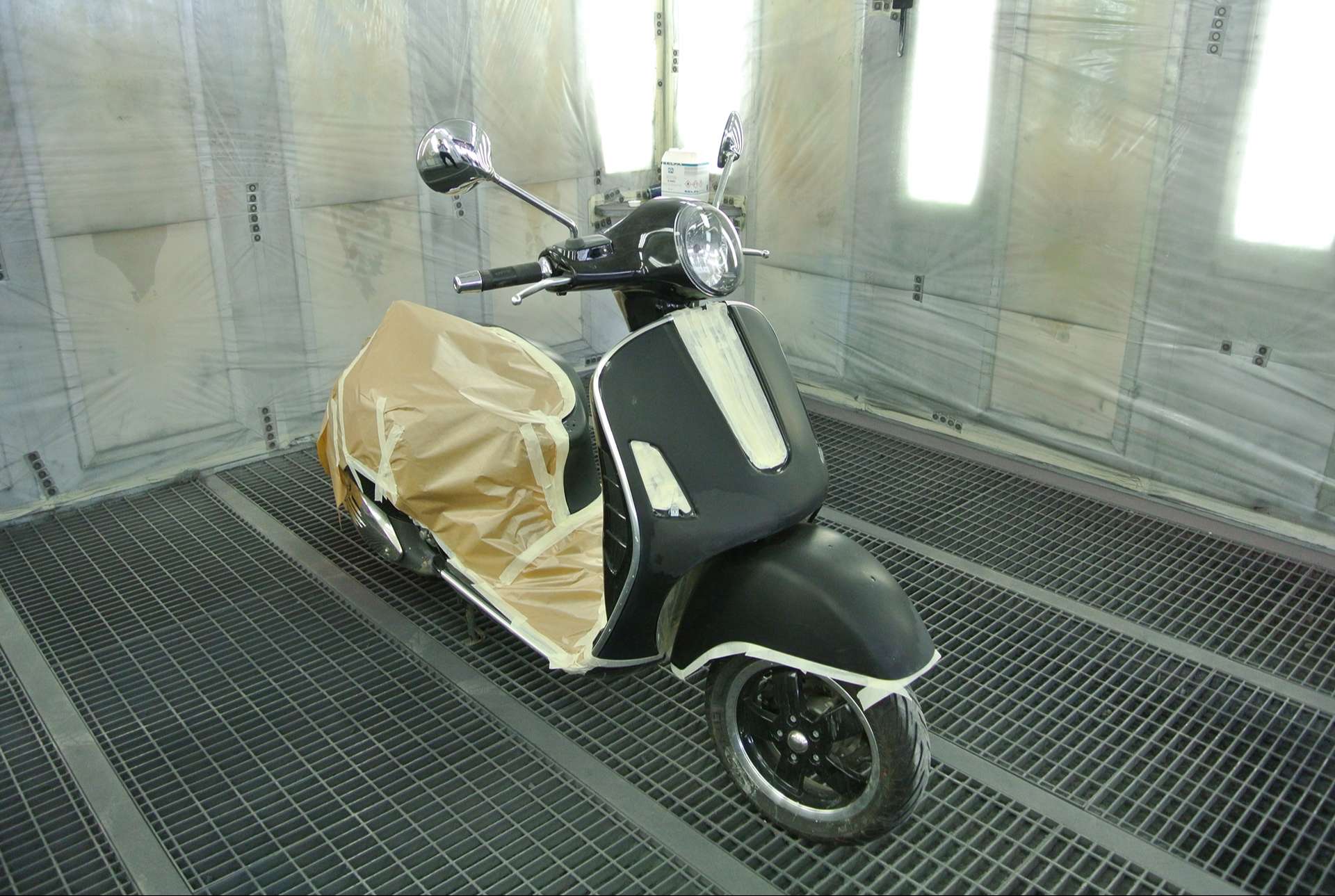 Scooter Vespa noir dans une cabine gyclage