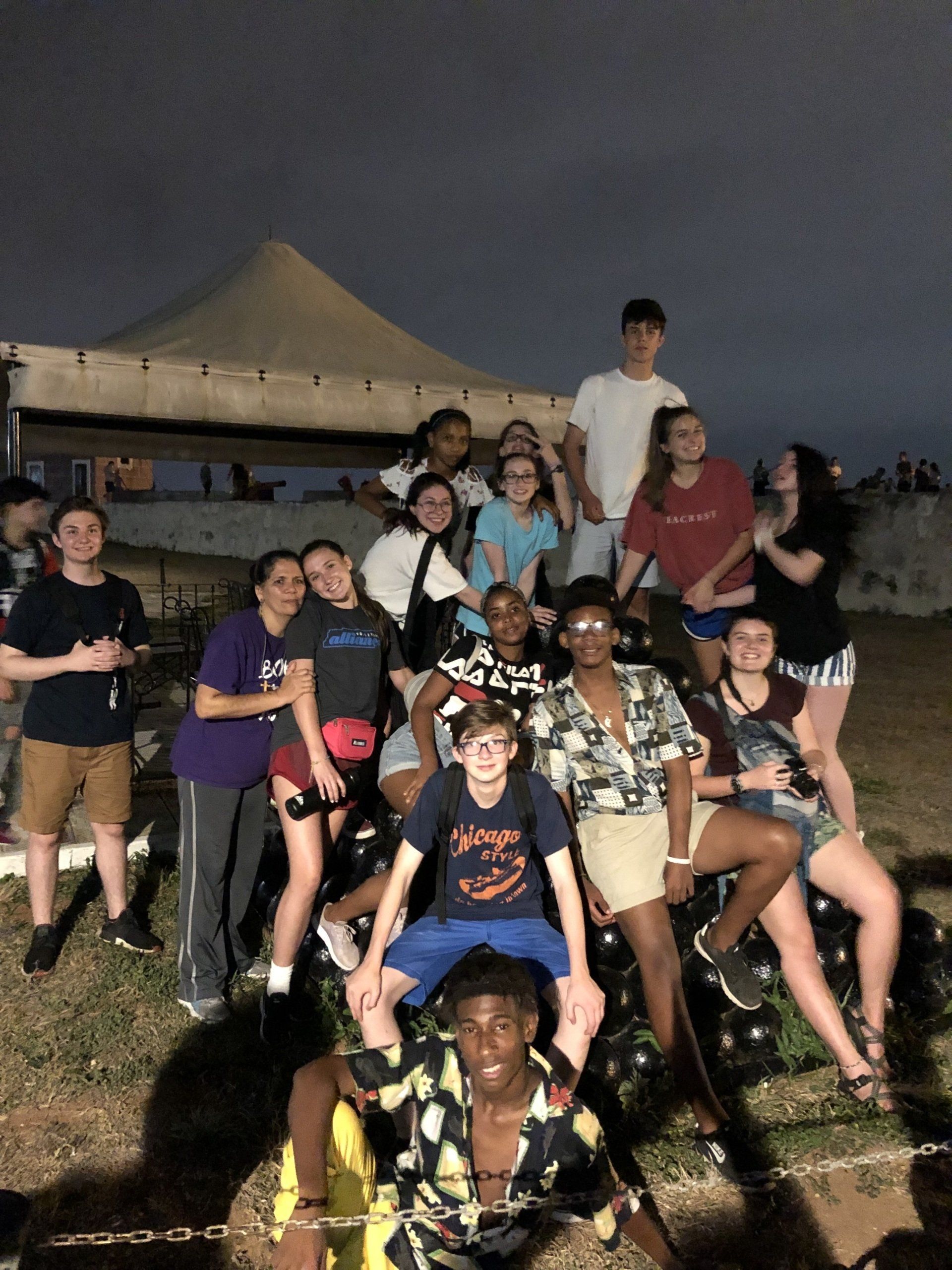 Group of people posing outdoors at night on a grassy area near a building.