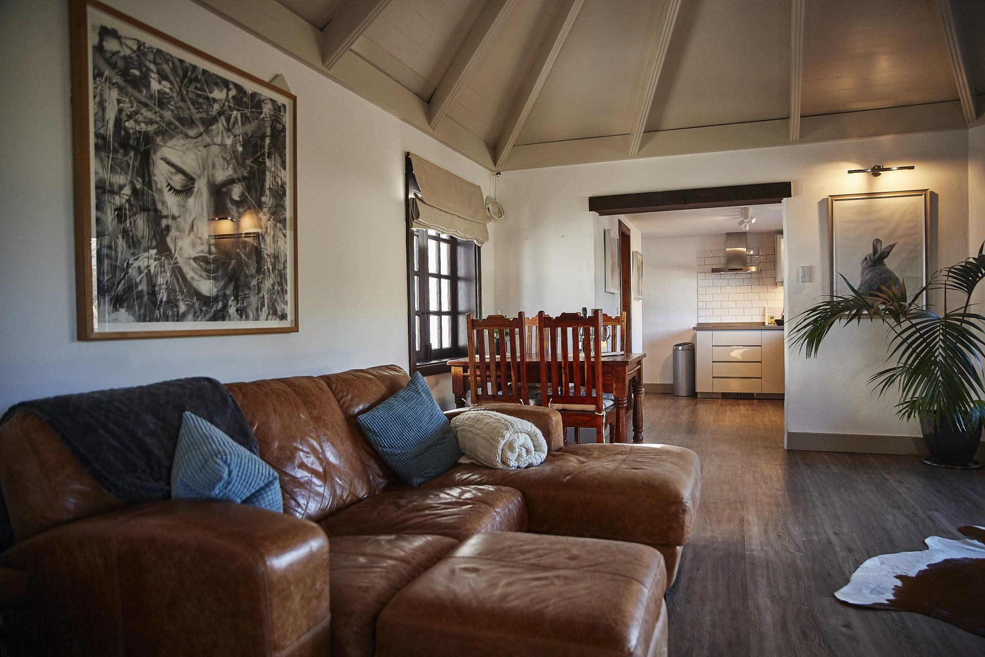 A living room with a brown leather couch and a painting on the wall.