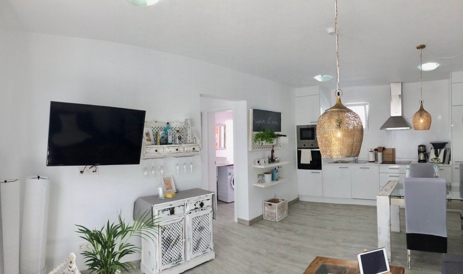 A living room with a flat screen tv and a kitchen.