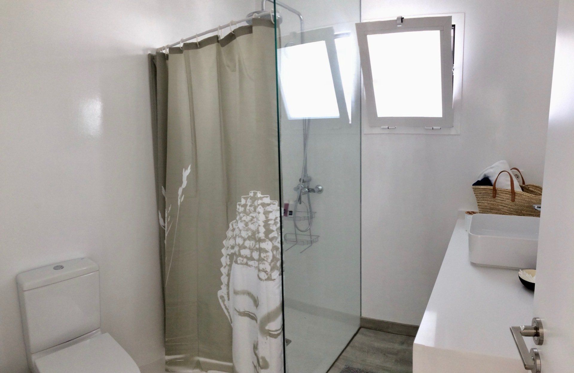 A bathroom with a toilet , sink , shower and window.