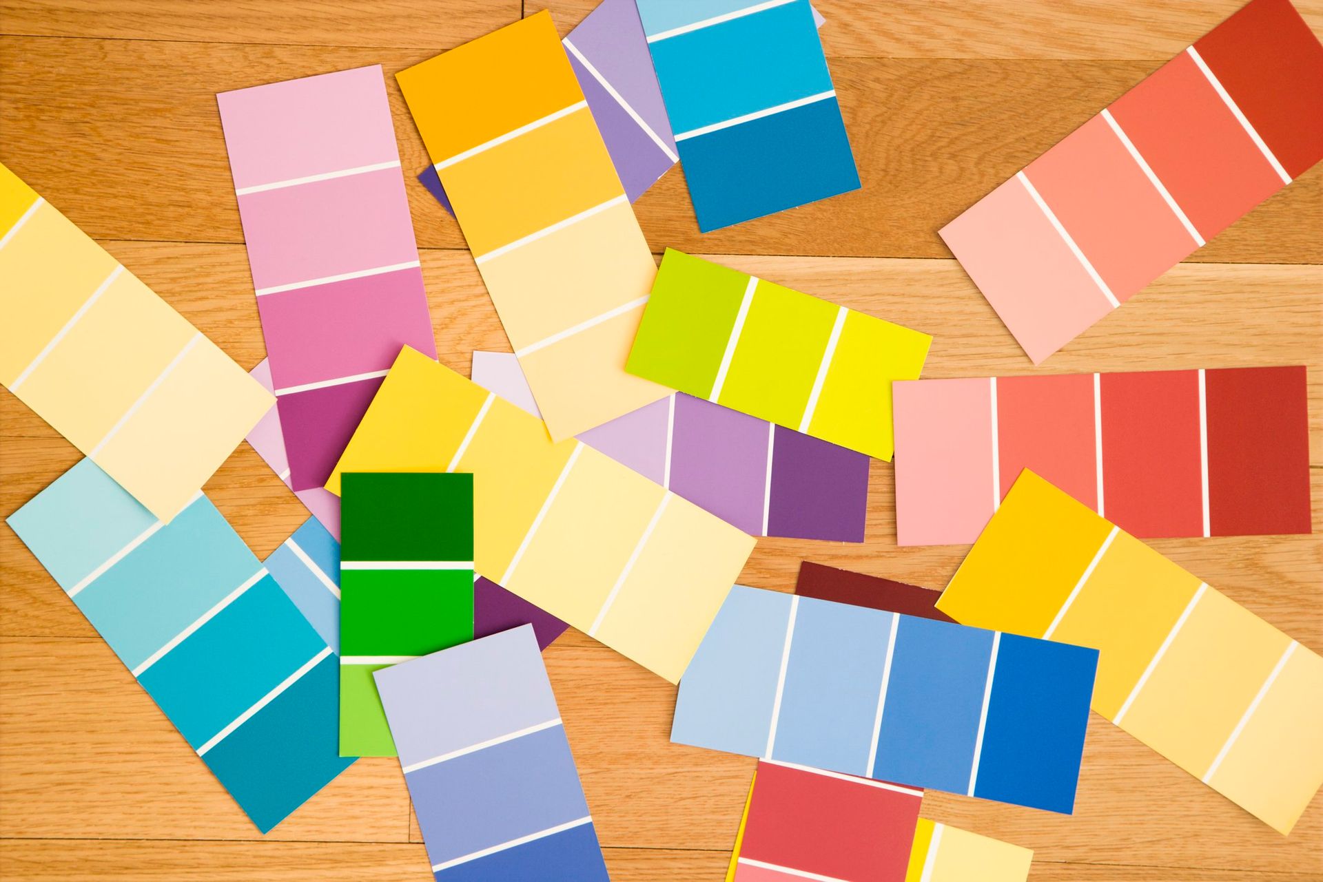 Colorful paper strips and folded shapes scattered on a wooden table in overlapping rows