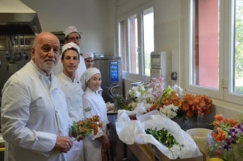 delle persone con dei camici bianchi e dei fiori colorati davanti