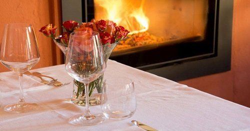 dei bicchieri sul tavolo, un vaso con dei fiori e un camino acceso