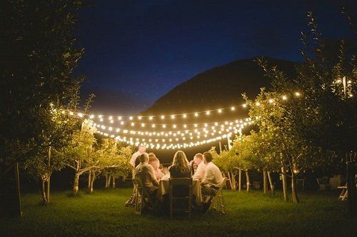 delle persone a tavola in un giardino e delle luci decorative