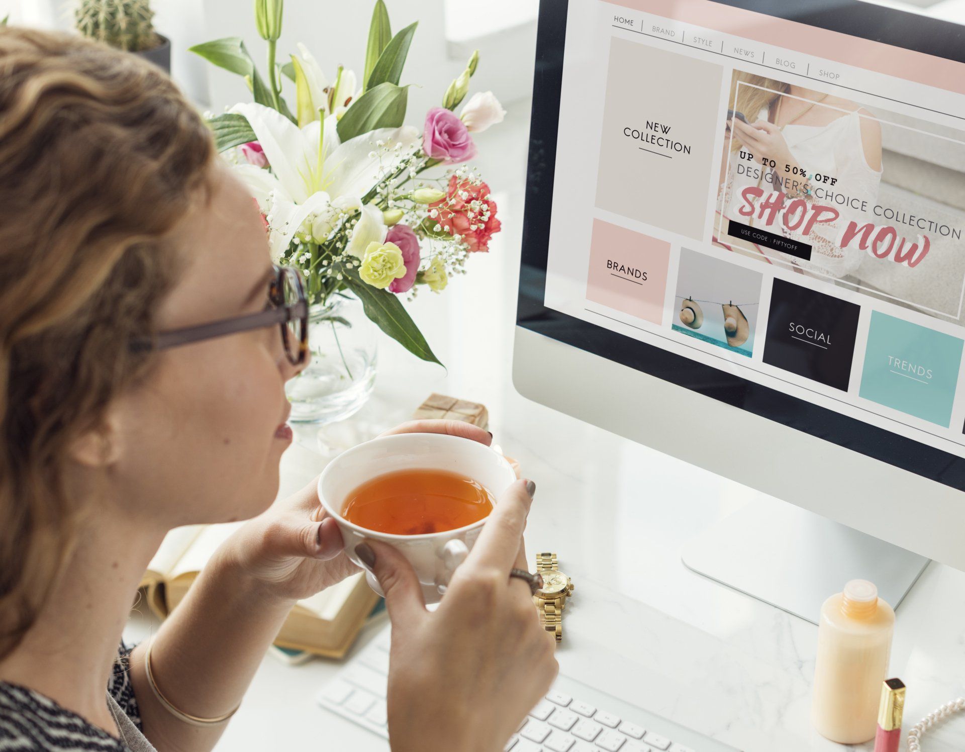 A woman is drinking tea in front of a computer screen that says shop now