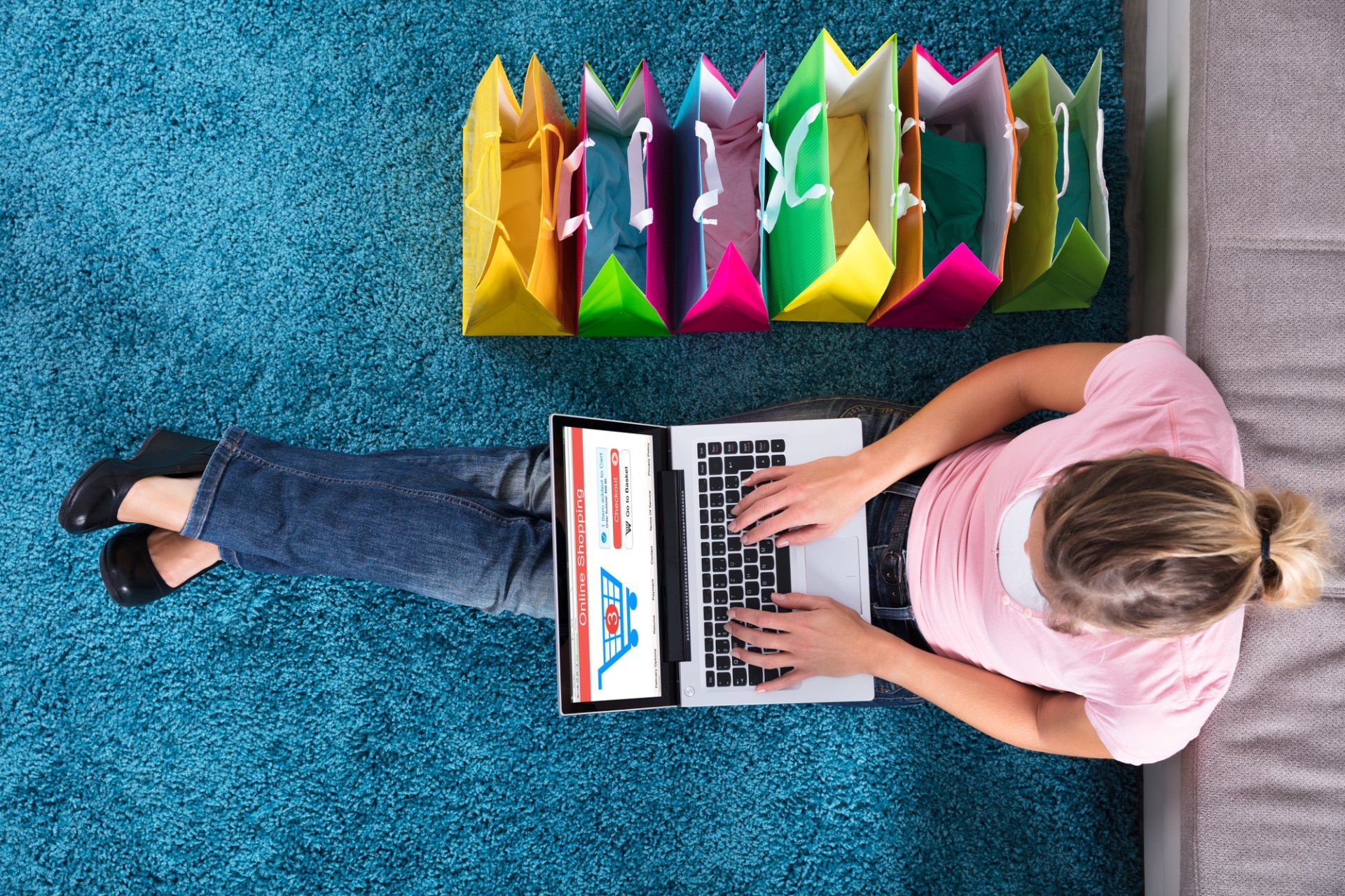 A woman is laying on the floor using a laptop