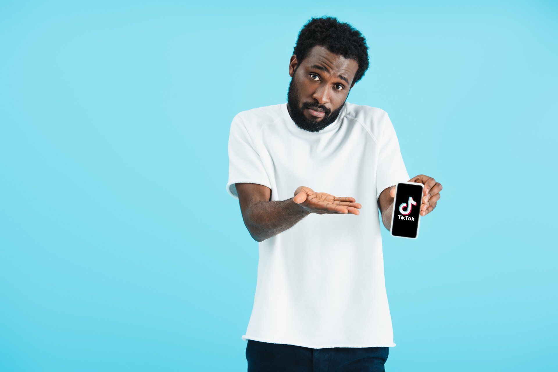 A man in a white shirt is holding a cell phone with a tiktok logo on it