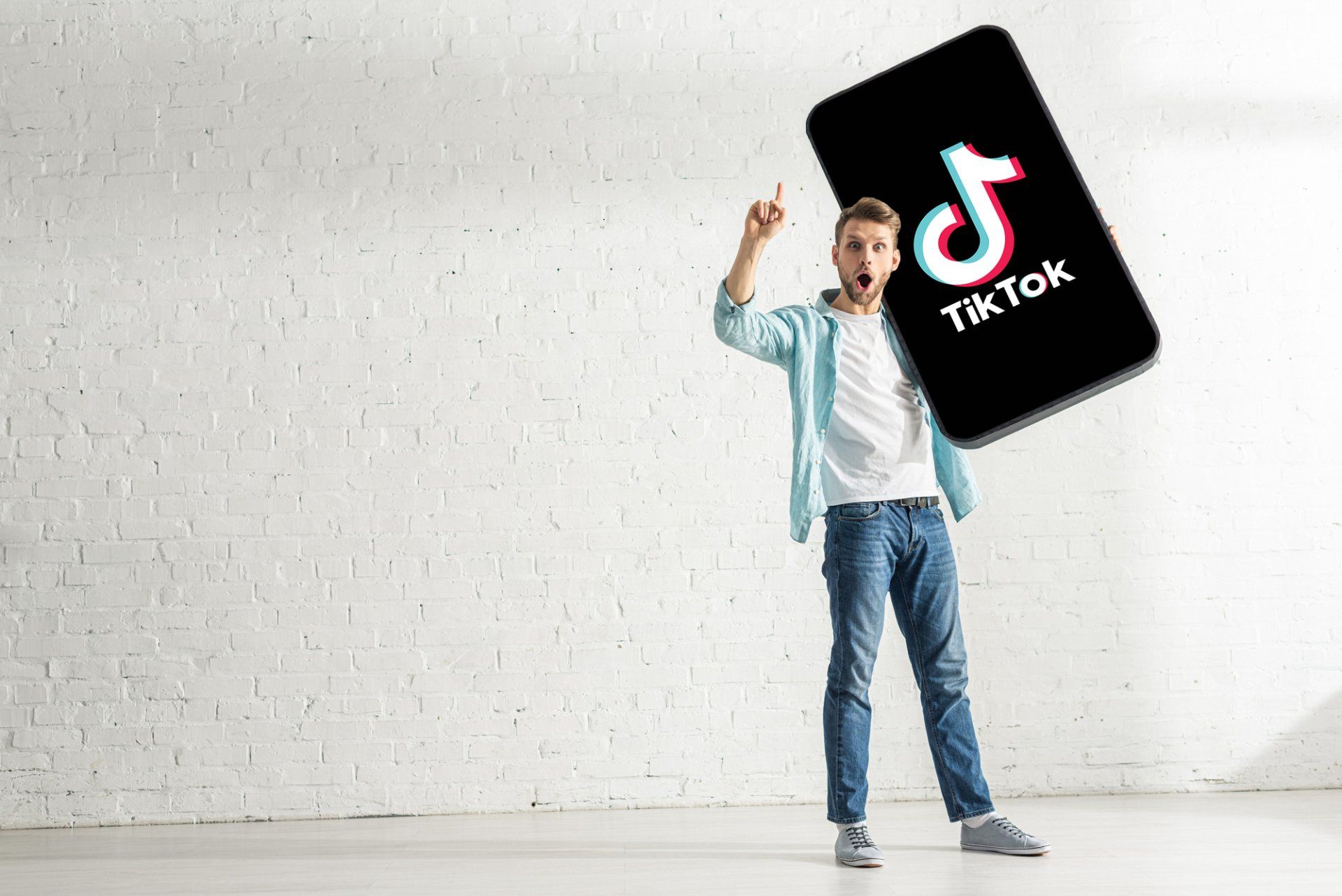A man is holding a cell phone with the tiktok logo on it