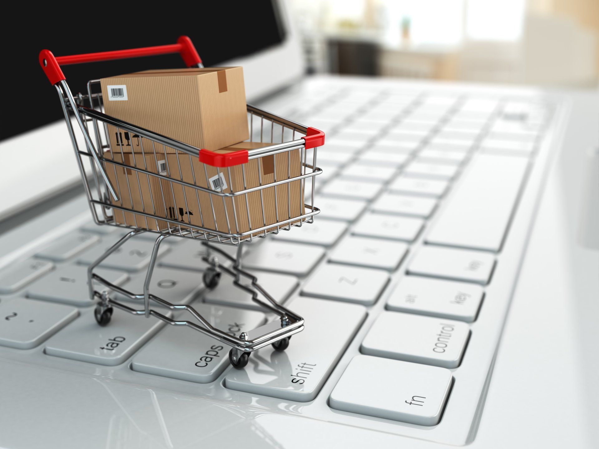 A shopping cart with boxes in it sits on a laptop keyboard