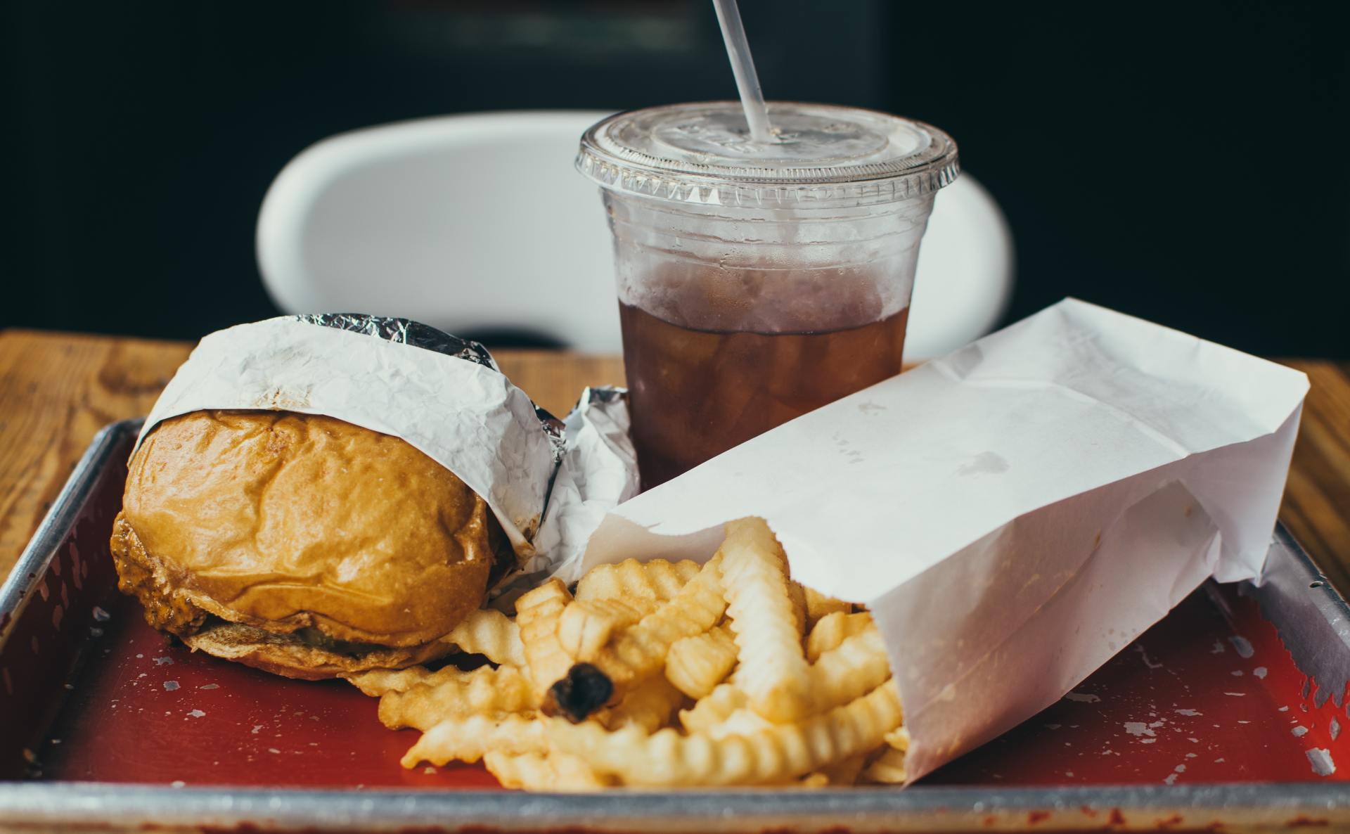 A hamburger and french fries on a tray with a drink