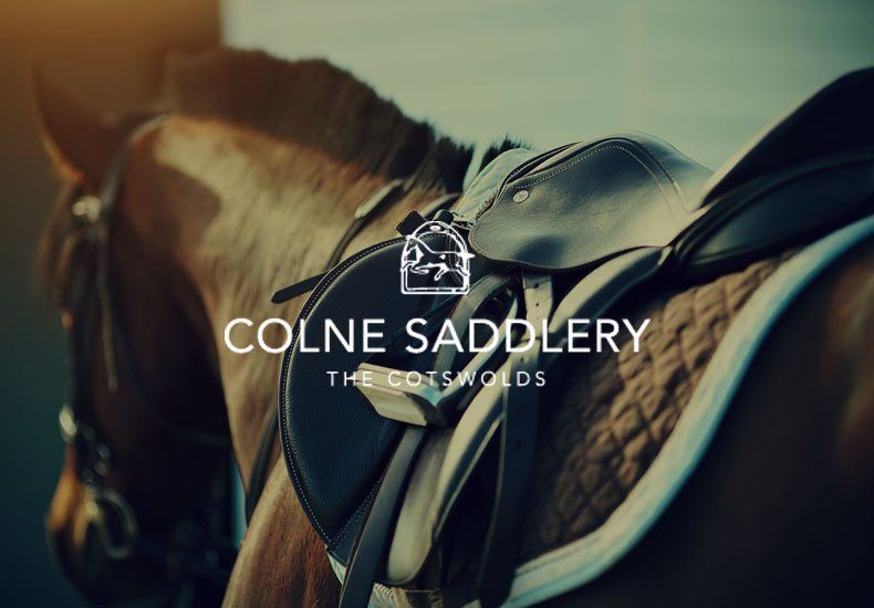 A close up of a horse with a saddle that says colne saddlery
