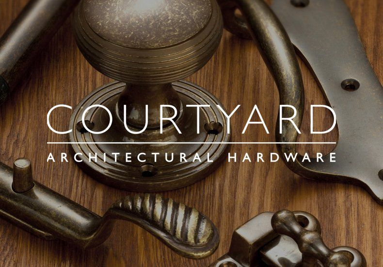 A brochure for courtyard architectural hardware is displayed on a wooden table