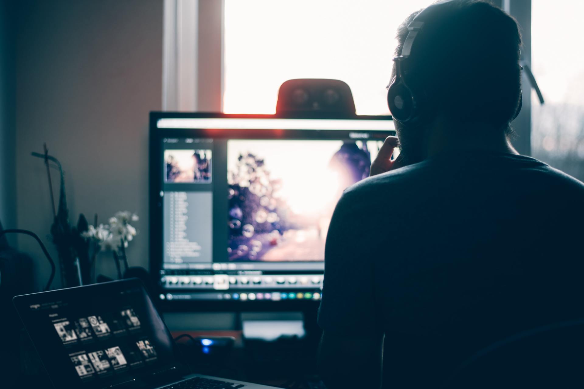 A man wearing headphones is looking at a computer screen