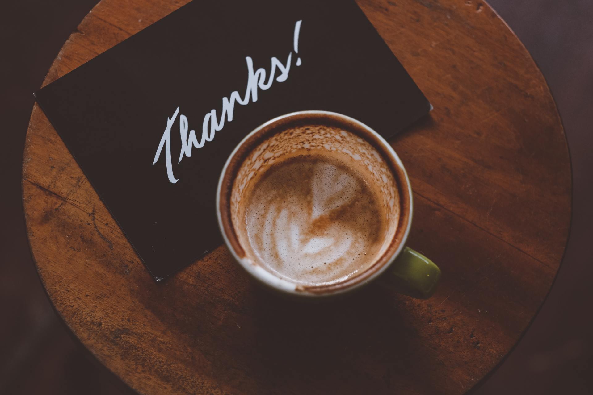 A cup of coffee sits next to a thank you card