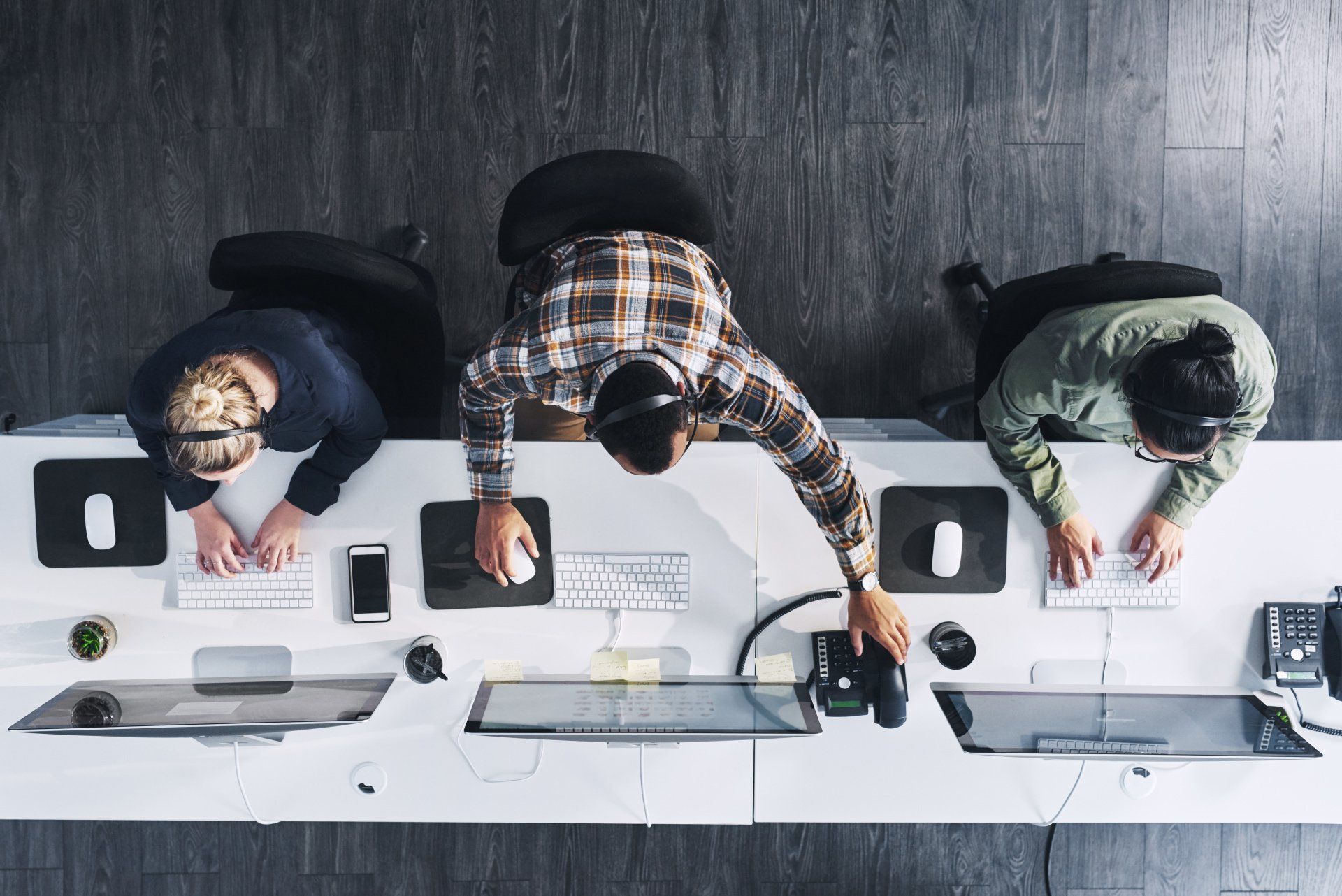 A group of people are sitting at a desk working on computers